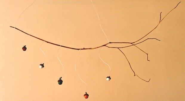 A mobile made with acorns and a branch.