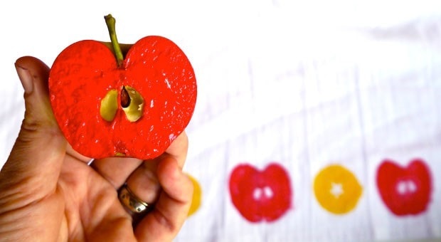 Half an apple covered in red paint, ready to use as a stamp.