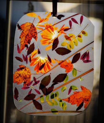 A window hanging made from leaves and contact paper.